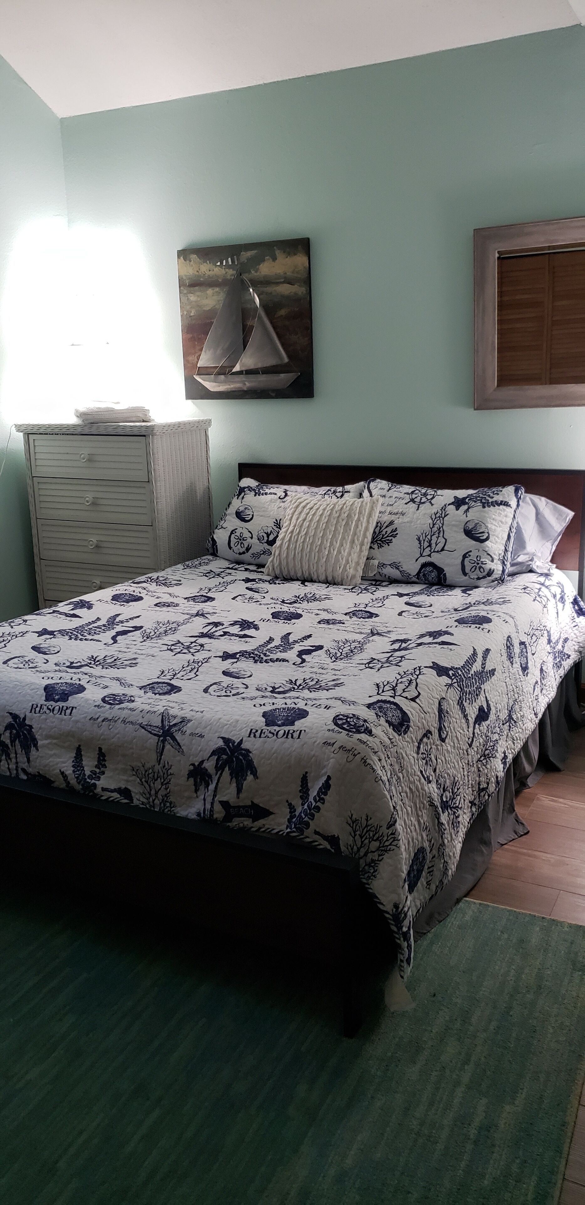 Un dormitorio con cama, cómoda, cuadro y aparador.