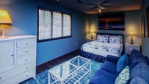 Un dormitorio con cama, cómoda, ventana con persianas, ventilador de techo y un cuadro en la pared.