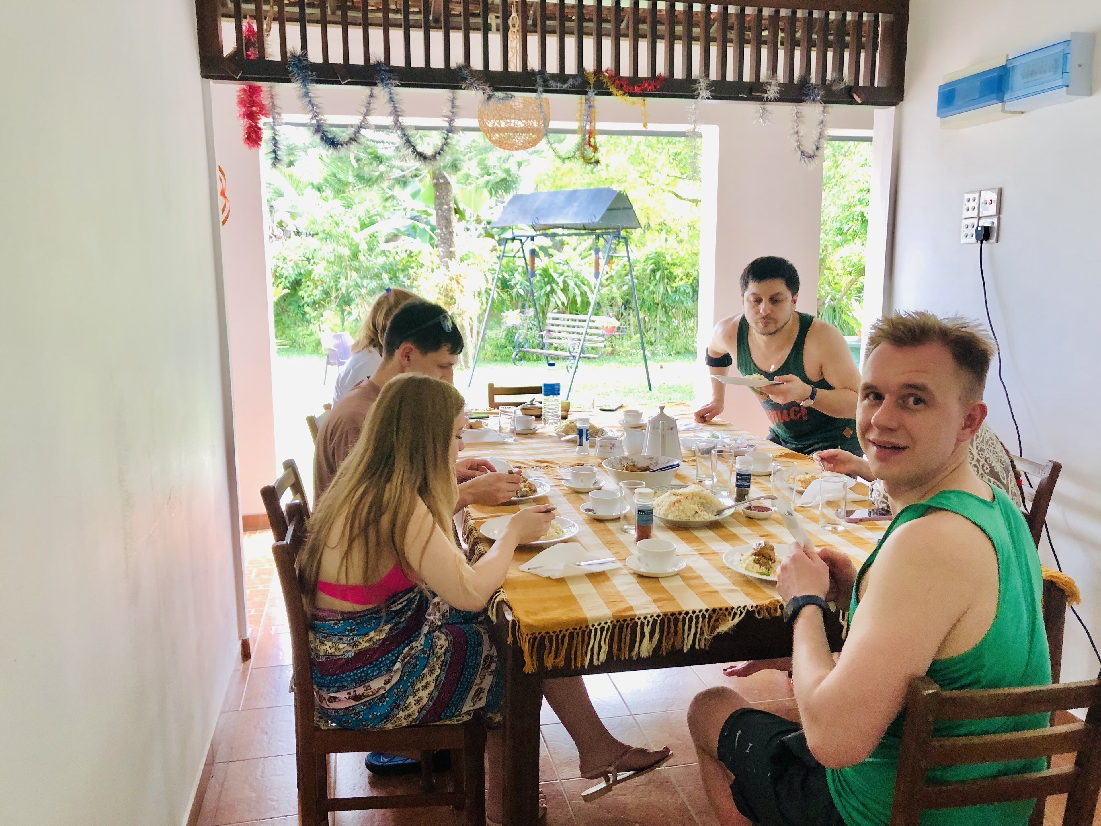 Uma sala de jantar com uma mesa posta para refeição, rodeada por cadeiras.