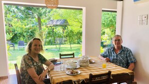 A dining area with a table set for two, a garden view, and a swing chair in the background. - Shanthi Boutique Villa (Hikkaduwa)
