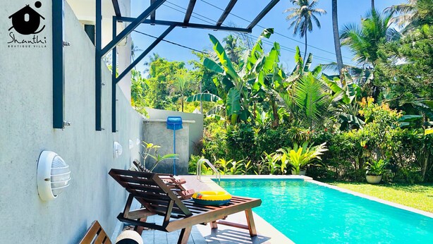 A poolside area with a wooden deck, lounge chairs, and a small pool. - Shanthi Boutique Villa (Hikkaduwa)
