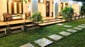A modern building with a covered outdoor seating area, potted plants, and a well-maintained lawn. - Shanthi Boutique Villa (Hikkaduwa)