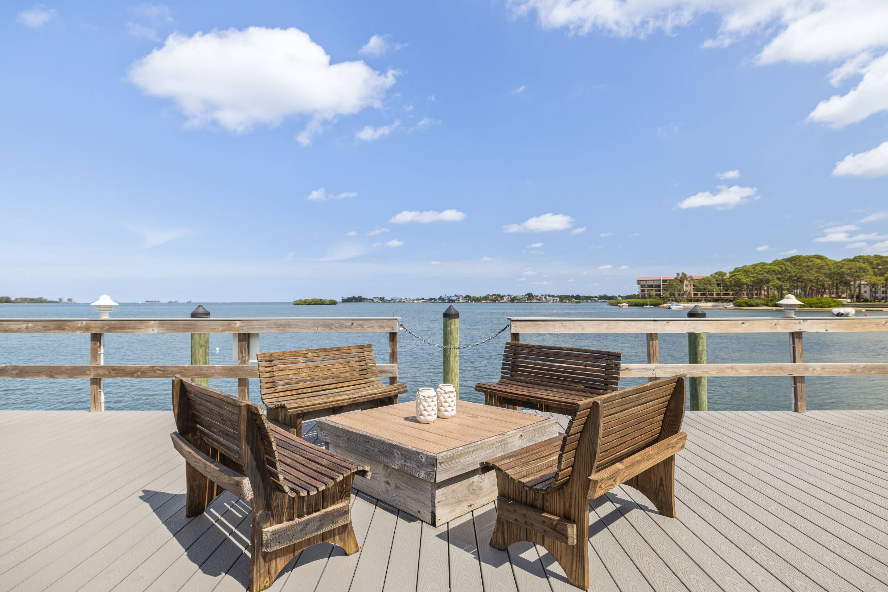 A wooden deck with a table and four benches overlooking a body of water.