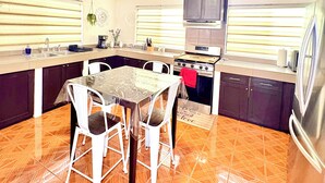 Una cocina con una mesa de comedor, sillas y estufa.