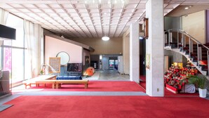 A spacious lobby with a red carpet, a staircase, and a vending machine. - Tabist Hotel Chouseikaku (Yatsushiro)