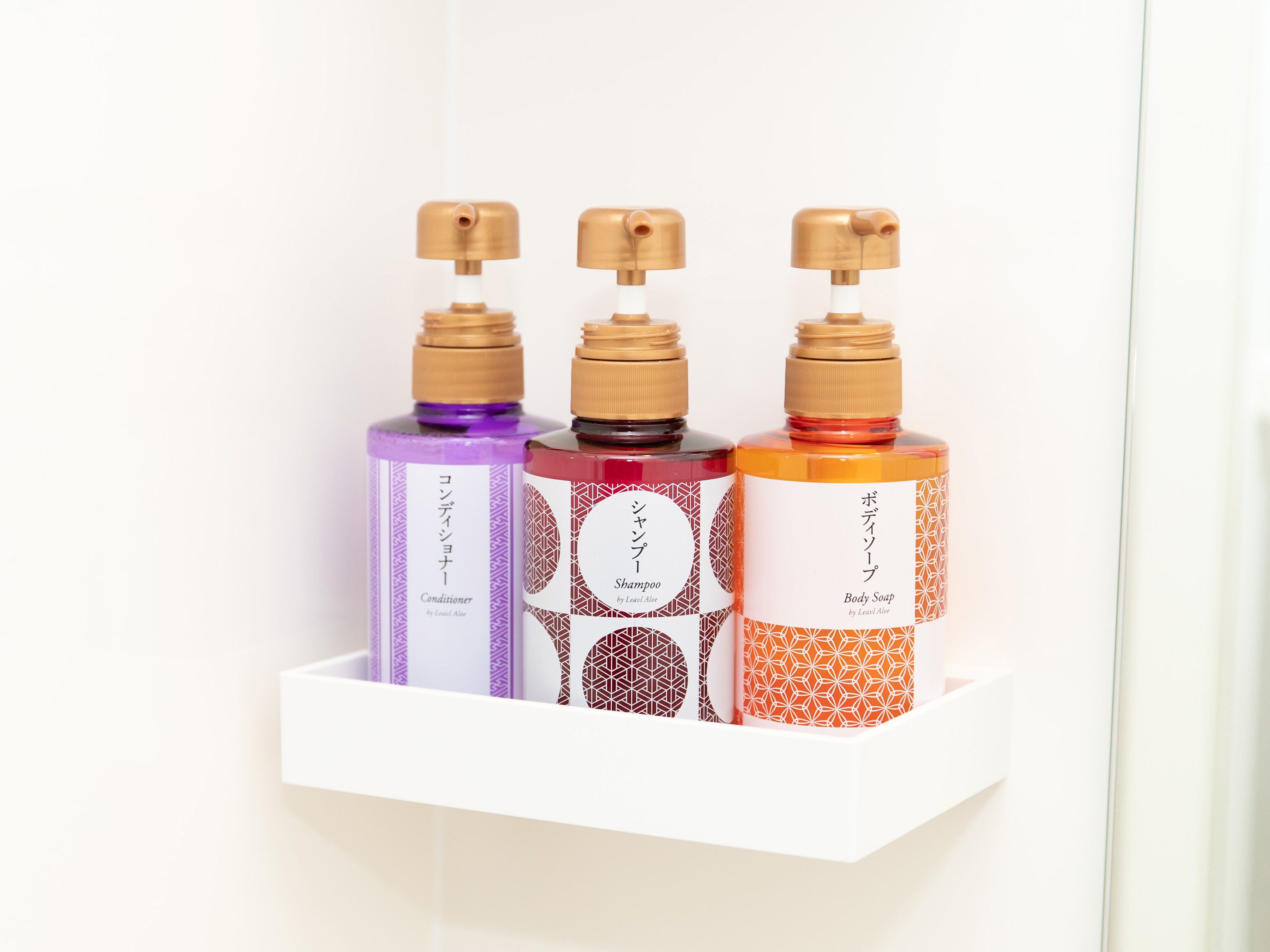 Three bottles of hair care products on a white shelf.