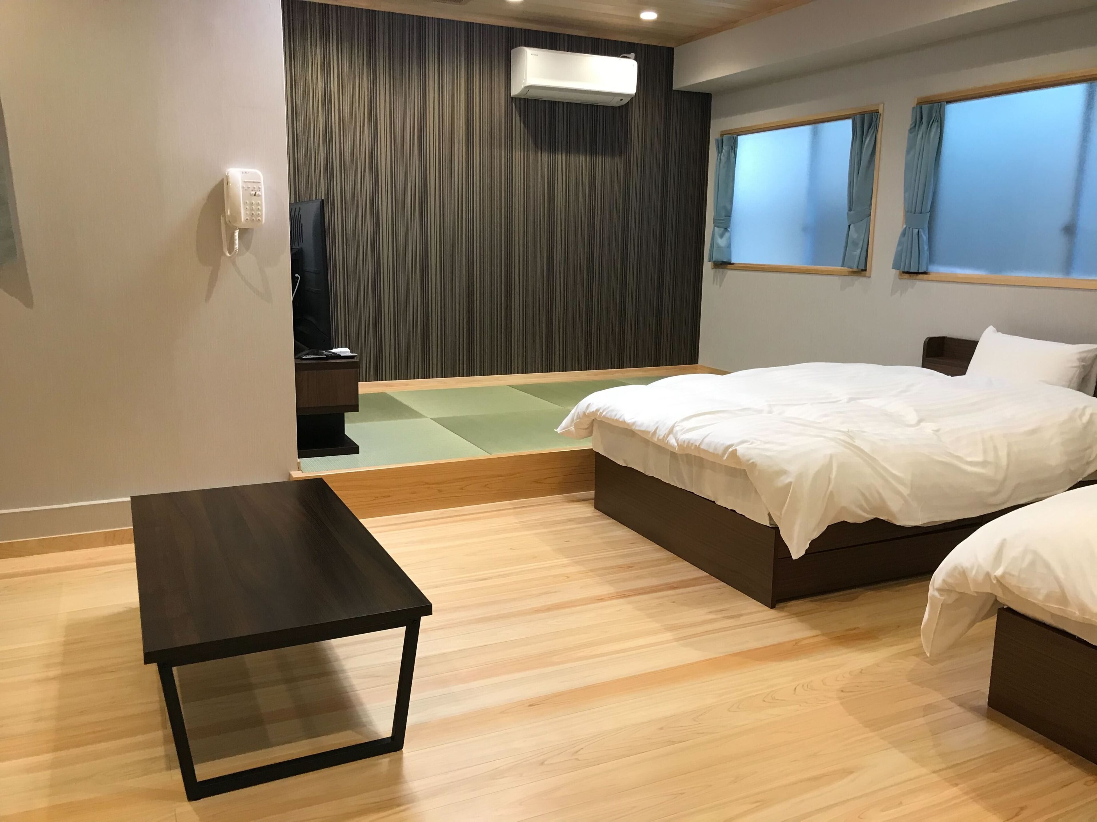 A hotel room with a bed, bedside table, and a small seating area.