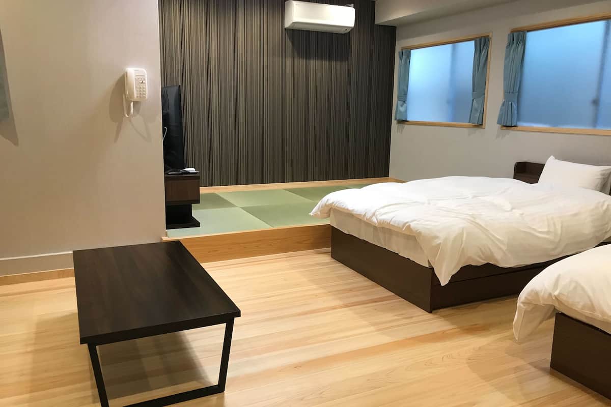A hotel room with a bed, bedside table, and a small seating area.