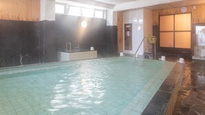 An indoor swimming pool with a tiled floor, a wooden wall, and a window allowing natural light. - Tabist Hotel Chouseikaku (Yatsushiro)