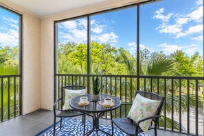 A balcony with two chairs, a small round table, and a potted plant.
