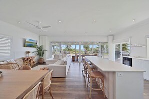 A spacious kitchen with a large island, dining area with wicker furniture, and a view of the outdoors.