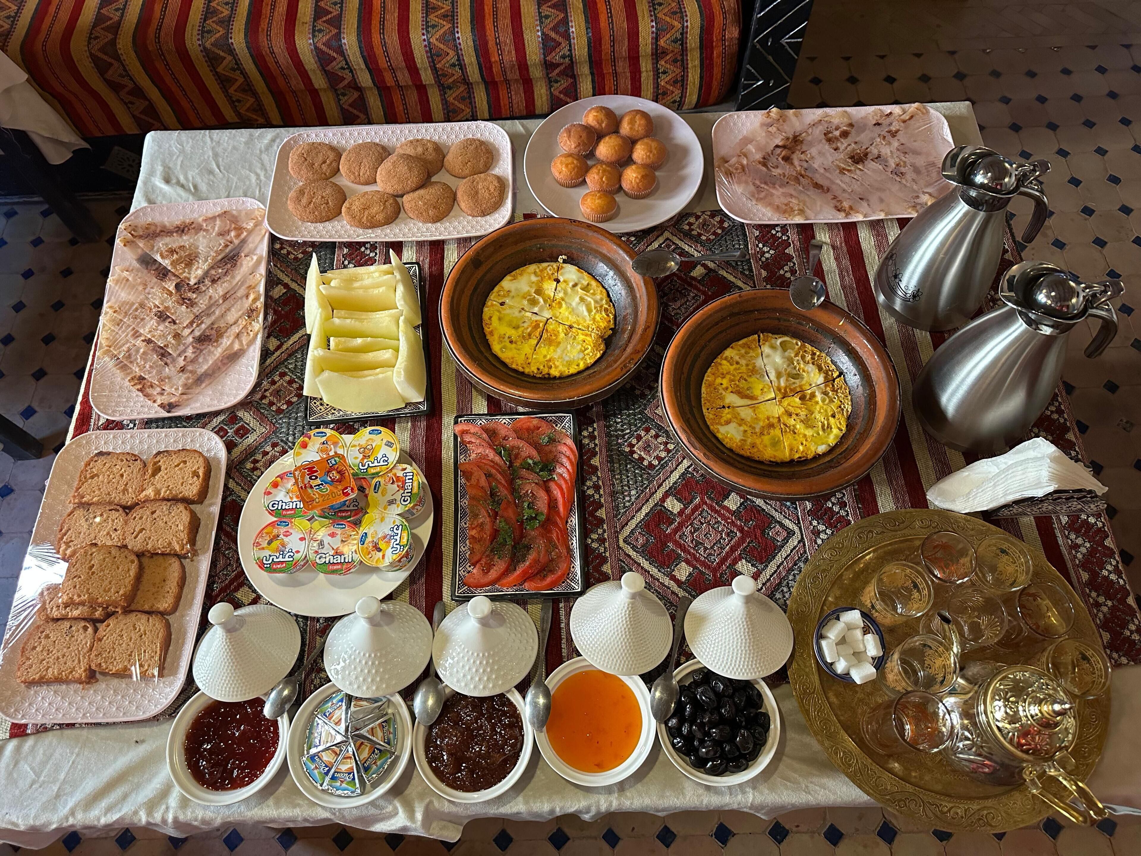 Et bord med forskelligt mad og bestik, blandt andet brød, kager og tilbehør.