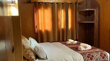 A hotel room with a bed, a small bedside table, a wardrobe, and a shower area.