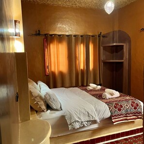 A hotel room with a bed, a small bedside table, a wardrobe, and a shower area.