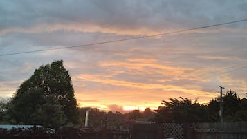 A sunset over a residential area with trees and a fence.