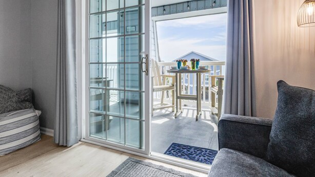 Ein Zimmer mit einer Schiebetür und einem Balkon mit Gartenmöbeln.