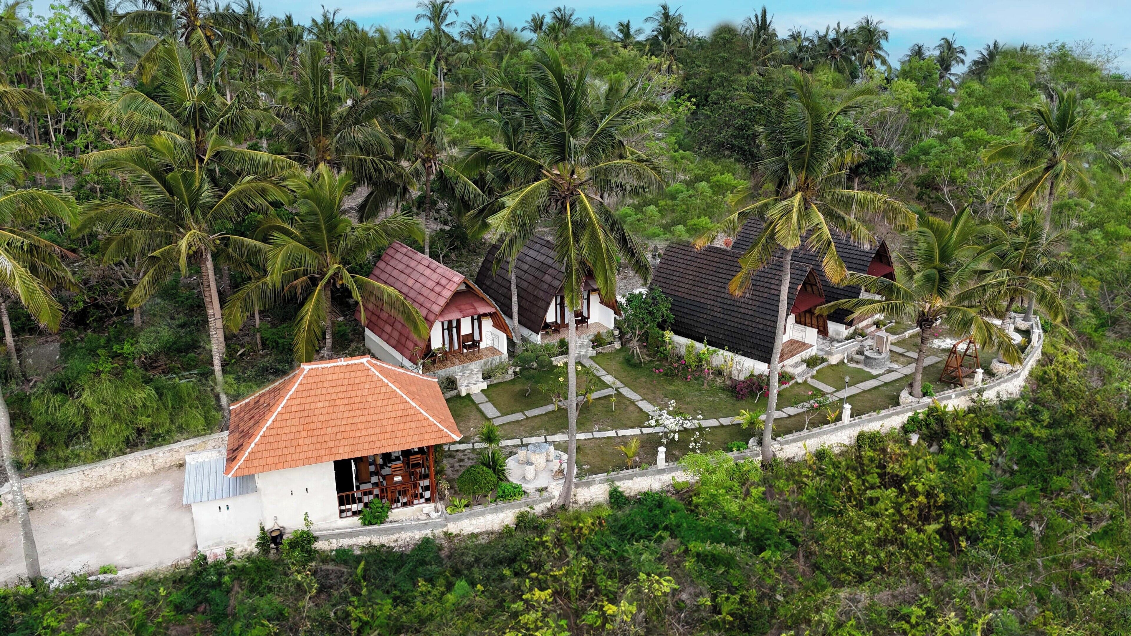 Un resort tropical con varias edificaciones tipo bungalow rodeado de densas palmeras.