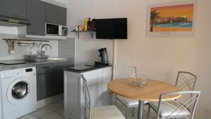 Una cucina funzionale con lavatrice, forno a microonde e un piccolo angolo ristoro con tavolo e sedie.