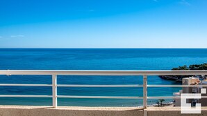 Un balcón con vistas al mar y un edificio de fachada blanca.