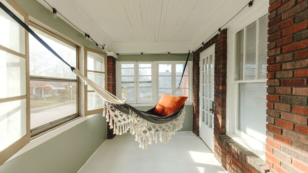 A hammock chair in a room with large windows, brick walls, and a white ceiling. - Historic Revival Midtown Memphis Free Parking (Memphis)