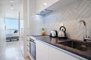 A modern kitchen with a herringbone tile backsplash, stainless steel appliances, and a large window offering a city view.