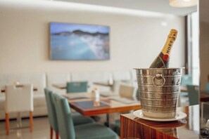 Eine Flasche Moët Champagner in einem Metallkübel auf einem Holztisch in einem modernen Hotelzimmer mit Blick auf eine verschneite Landschaft.