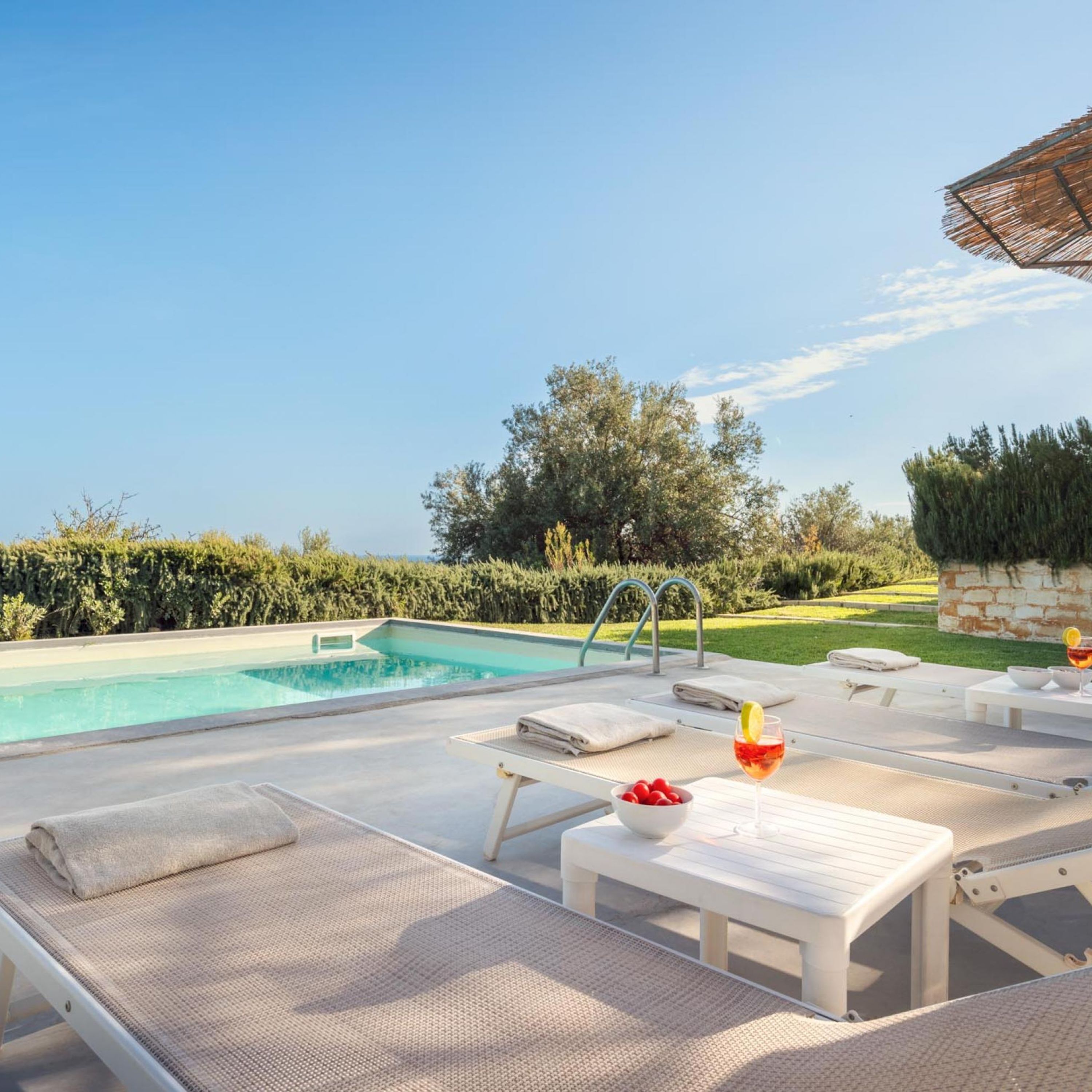 A poolside area with lounge chairs, a pool, and a view of the landscape.