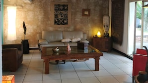 A living room with a sofa, coffee table, and a patterned rug. - BAS DE VILLA cosy, wooded garden with swimming pool, very quiet, town center. (Nouméa)