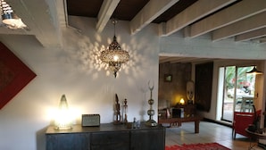 A spacious living area with a large cabinet, decorative items, and a red rug. - BAS DE VILLA cosy, wooded garden with swimming pool, very quiet, town center. (Nouméa)