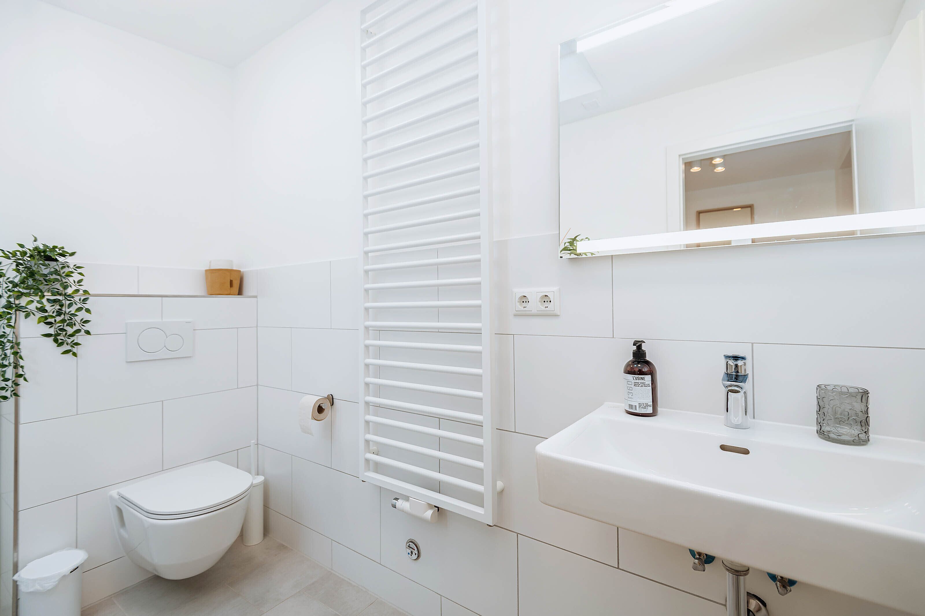 A modern bathroom with a toilet, a white sink, and a mirror.