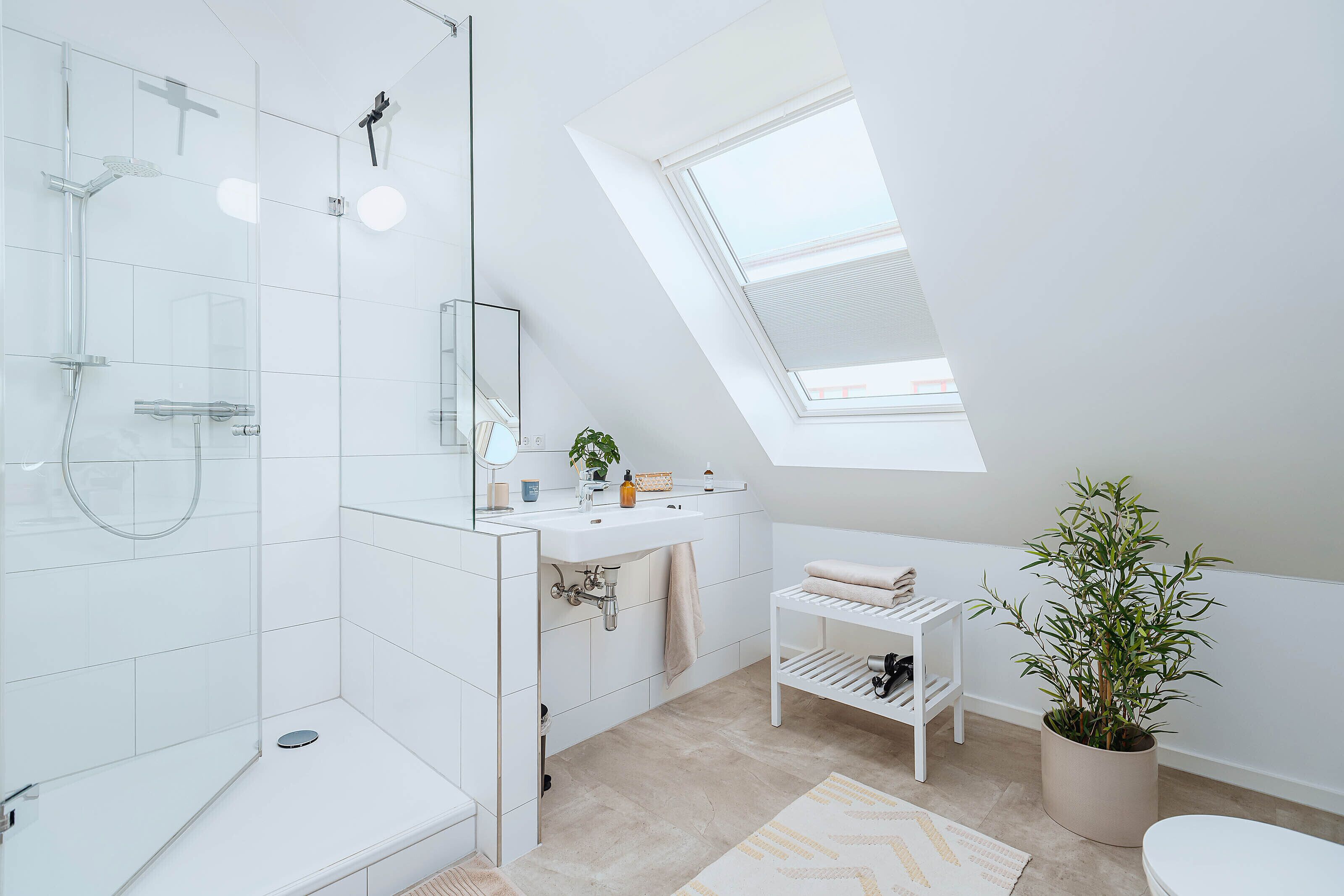 A modern bathroom with a skylight, a shower, a sink, and a toilet.