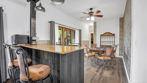 Une cuisine moderne dotée d’un îlot central, d’un coin repas avec une table et des chaises en bois, et d’un ventilateur de plafond.