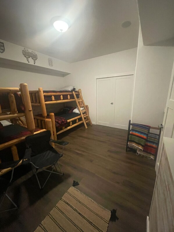 A room with a bunk bed, a desk, a chair, and a small rug.