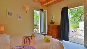 Un dormitorio con cama, cómoda, ventana con cortinas y vistas al exterior.