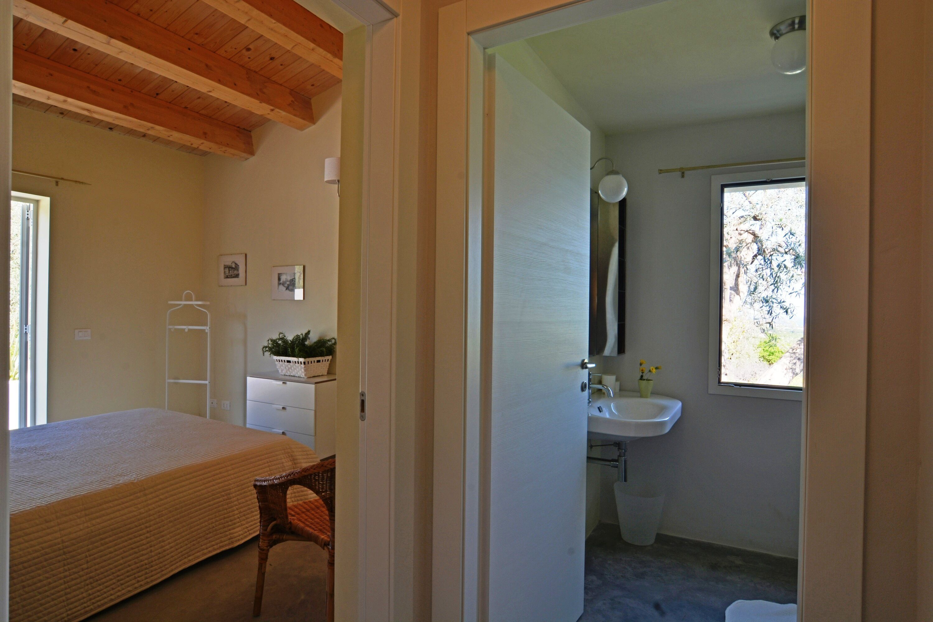 Un dormitorio con cama, una silla, cómoda y ventana.