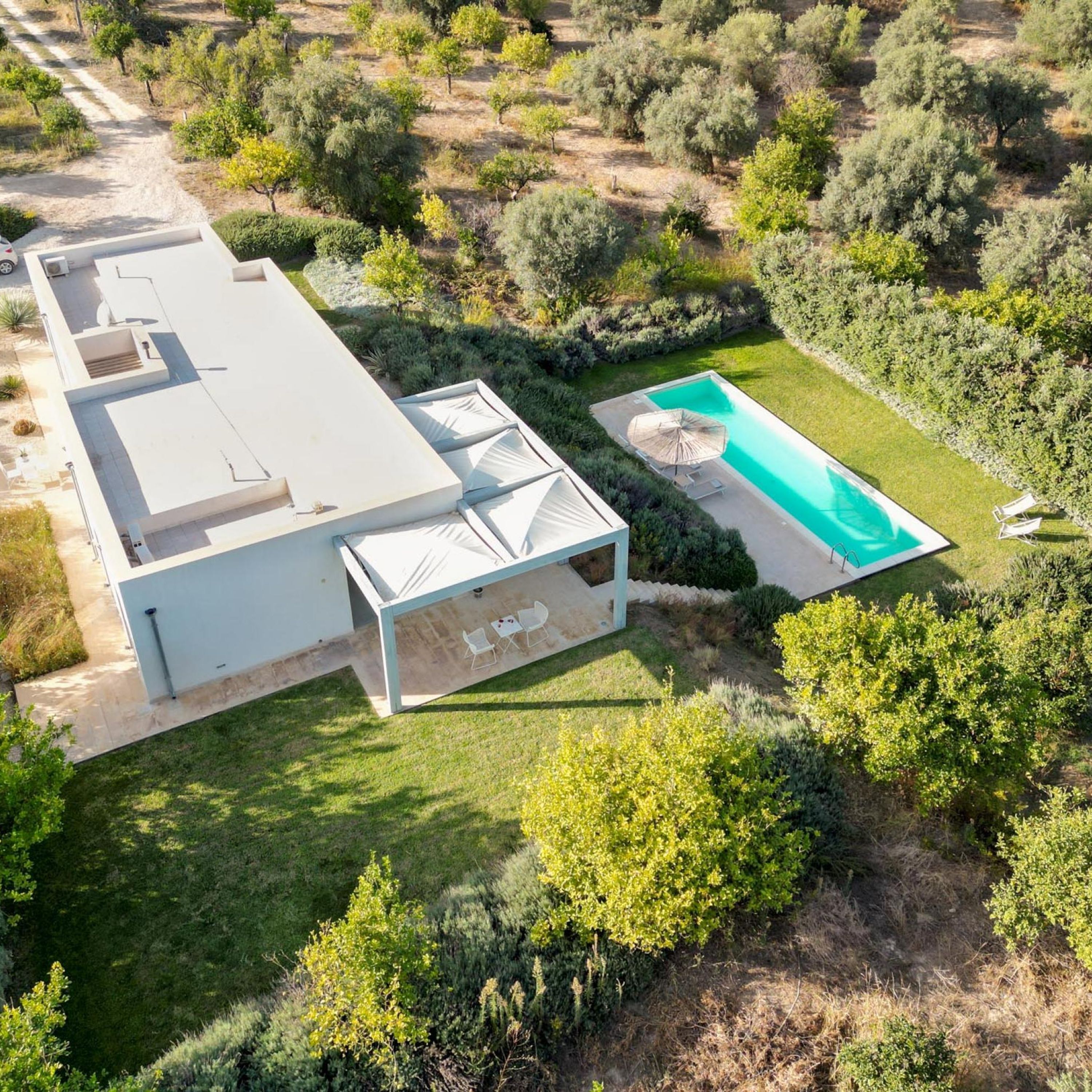 Ein modernes Haus mit Swimmingpool, überdachter Terrasse und gepflegtem Garten.