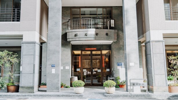A hotel entrance with a glass door, a balcony, and potted plants. - LAR Suite (Taichung)