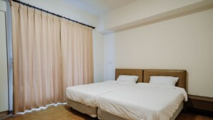 A bedroom with a large bed, wooden flooring, and a curtain on the window. - LAR Suite (Taichung)