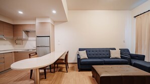 A modern kitchen with a dining table and chairs, a sofa, and a small ottoman. - LAR Suite (Taichung)
