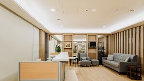 A modern living room with a sofa, armchairs, a coffee table, and a small table. There is a partition with a window and a door. - LAR Suite (Taichung)