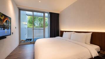 Een moderne hotelkamer met een groot bed, een flatscreen televisie aan de muur en een schuifdeur naar een buitenruimte.