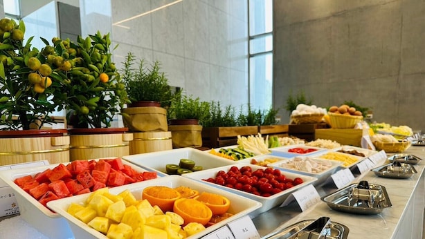Un bufé con diversas frutas y verduras, incluyendo sandía, piña y naranjas.