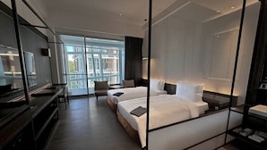 Una habitación de hotel moderna con una cama grande, un escritorio y una silla. Una ventana amplia ofrece vistas al exterior.