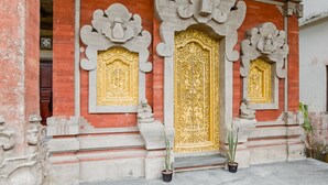 Fachada de edificio con puertas doradas ornamentadas y estatuas.