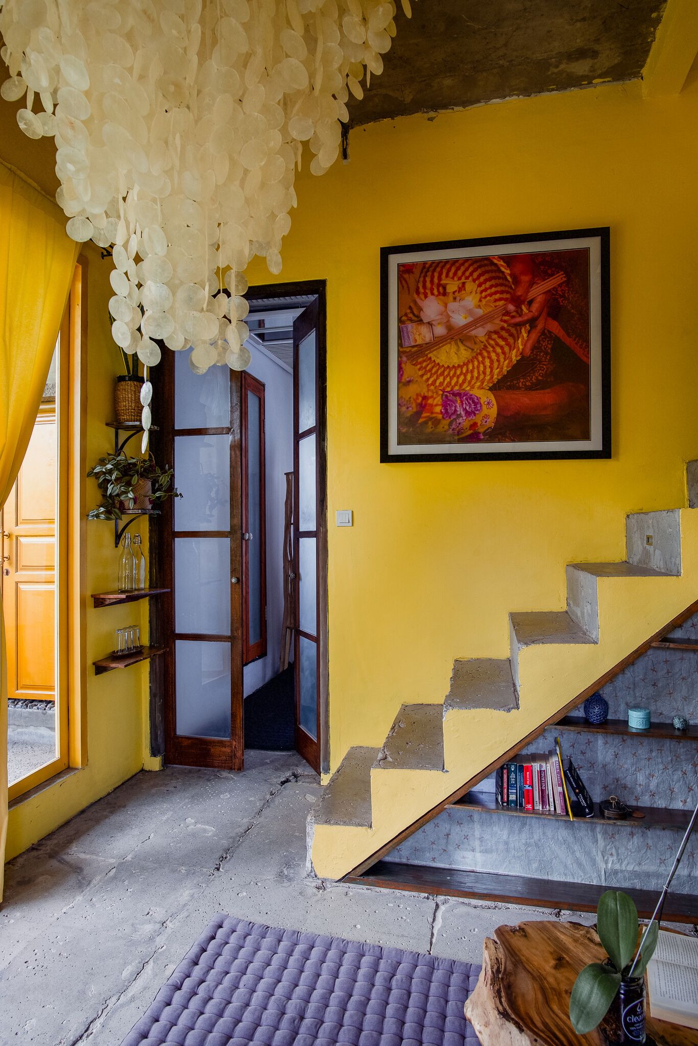 A staircase with a yellow wall and a framed painting.