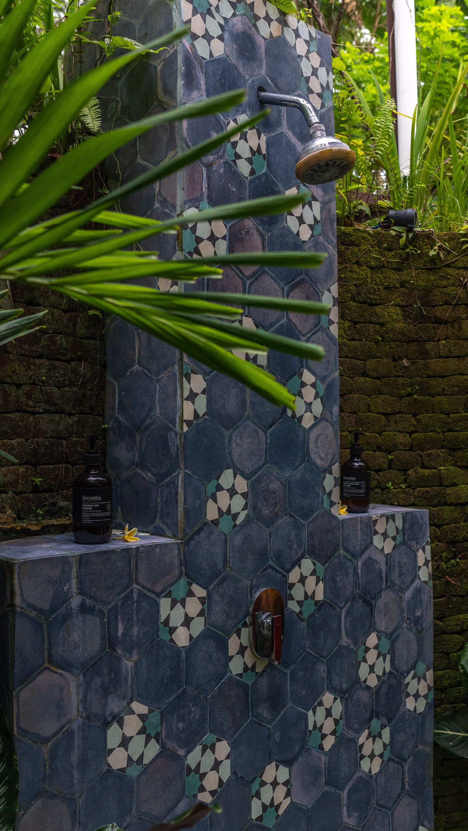 A hexagonal tiled wall with a showerhead and a faucet.