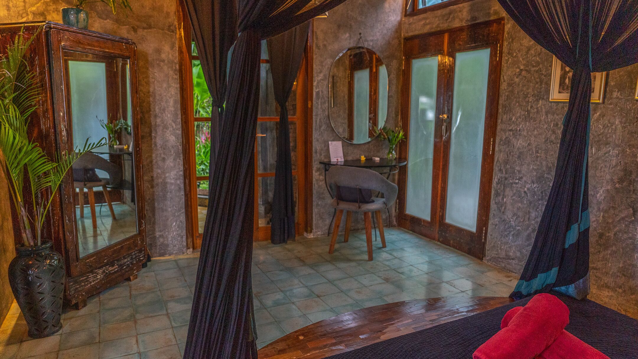 Une pièce avec un grand miroir, une chaise, un bureau et un canapé rouge.