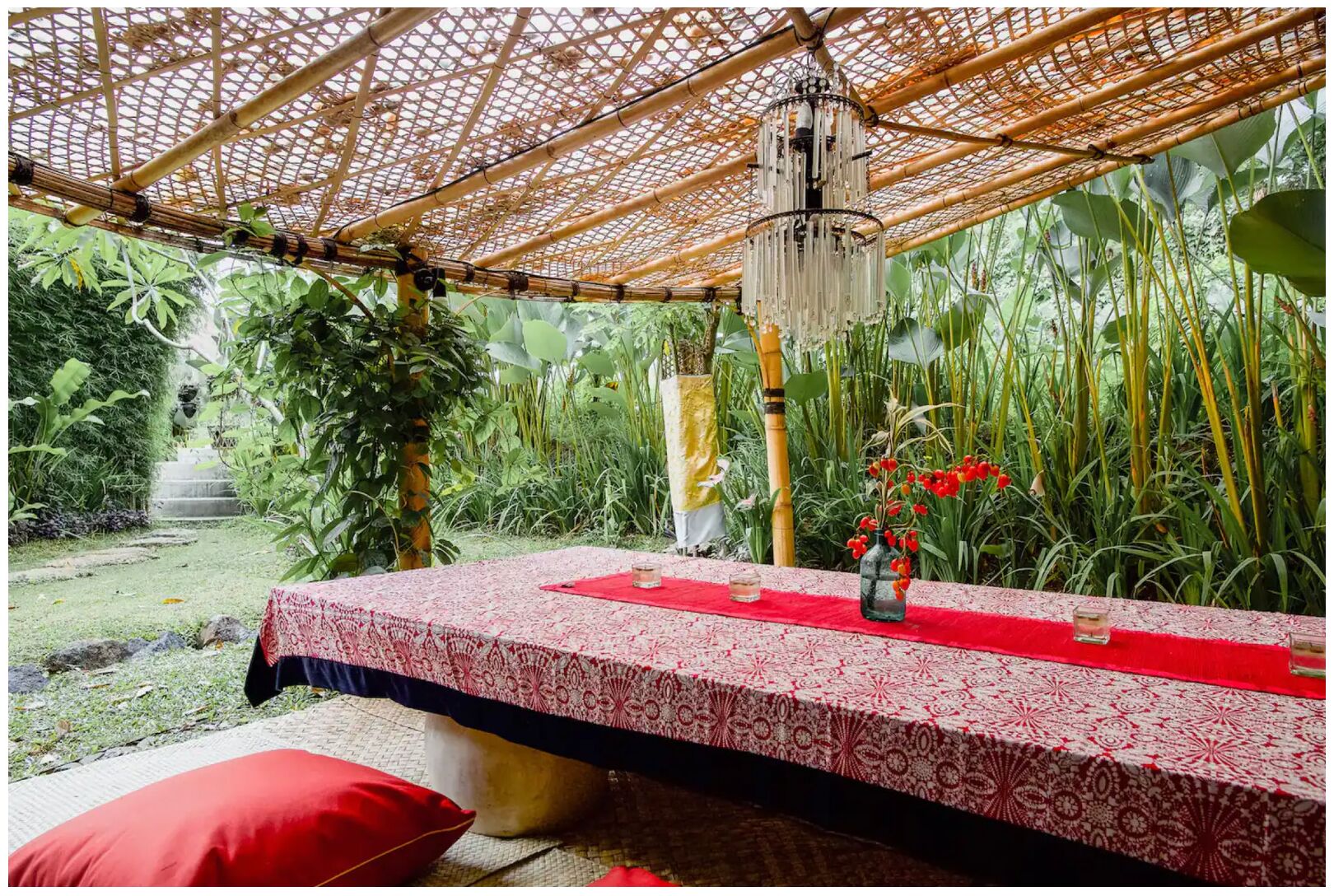 A room with a bed under a bamboo canopy, surrounded by lush greenery.