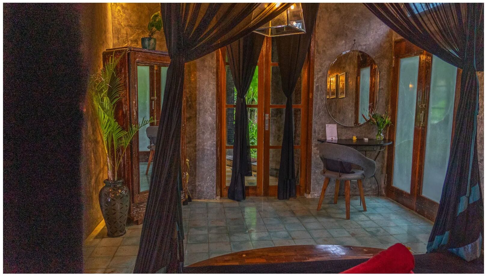 A room with a large window, a chair, a table, and a potted plant.