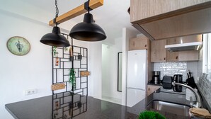 A modern kitchen with a black countertop, wooden cabinets, and a hanging light fixture.
